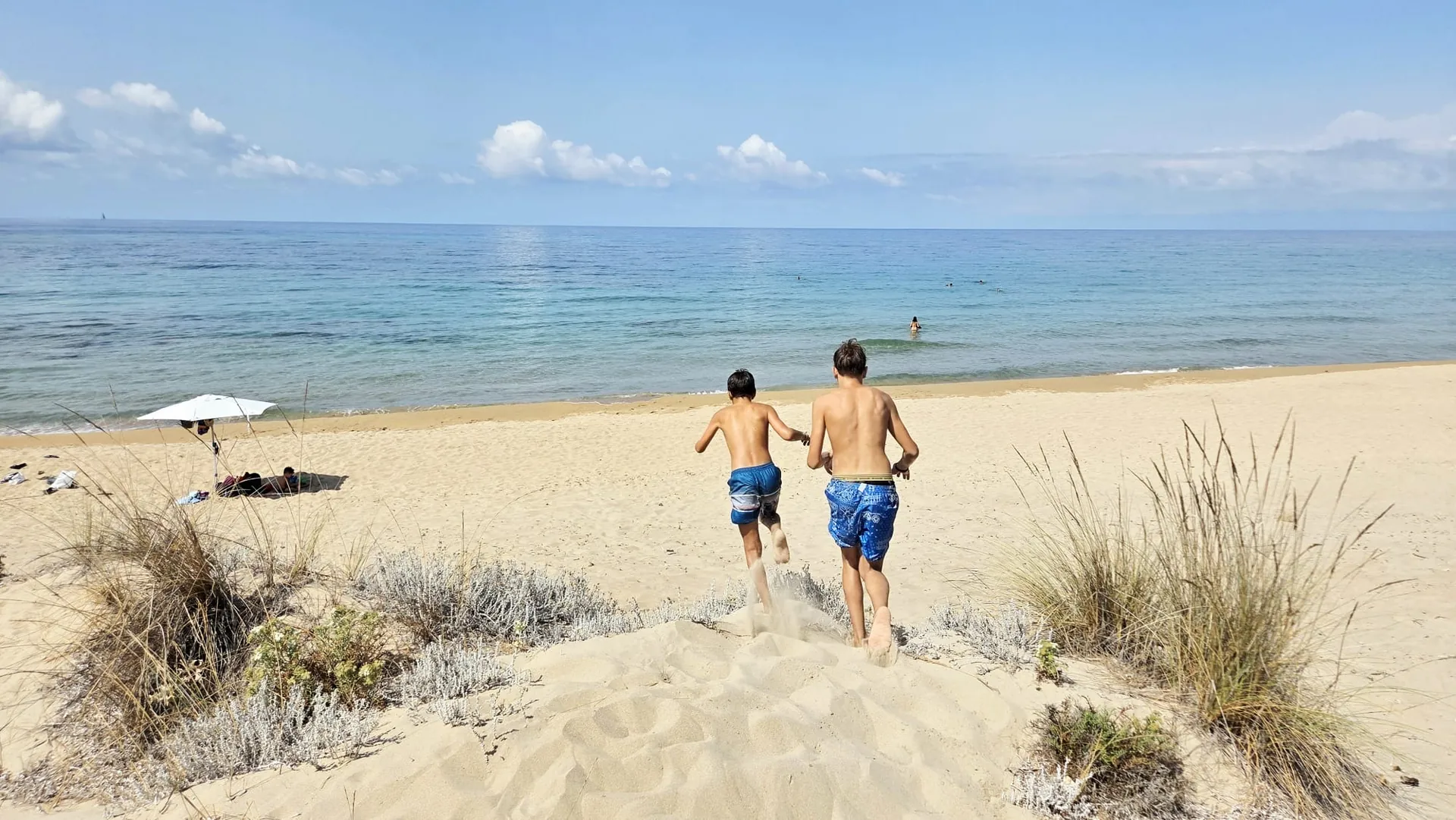 Due bambini corrono sulla spiaggia verso il mare