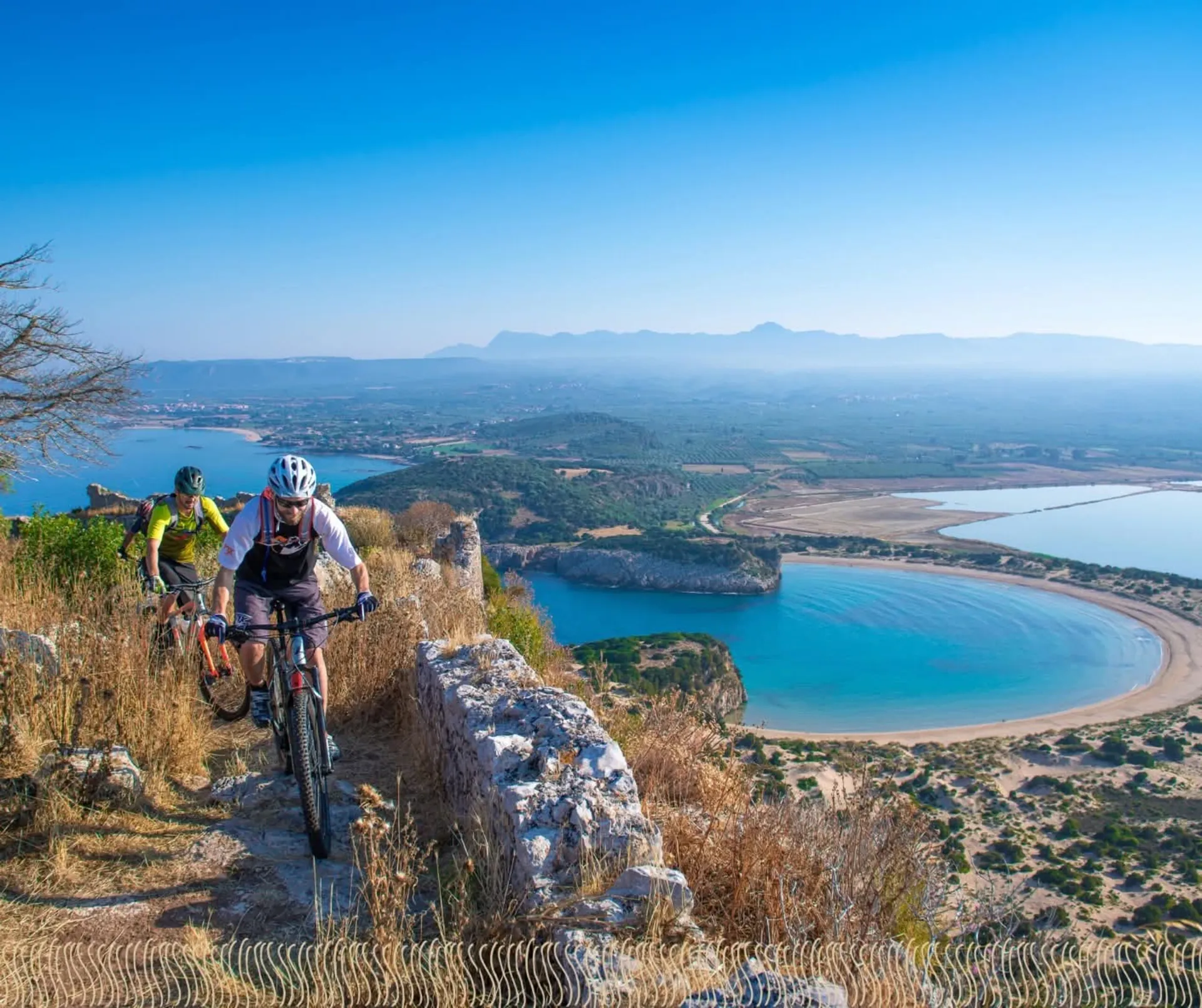 Due ciclisti in mountain bike sul sentiero sopra la baia di Voidokilia