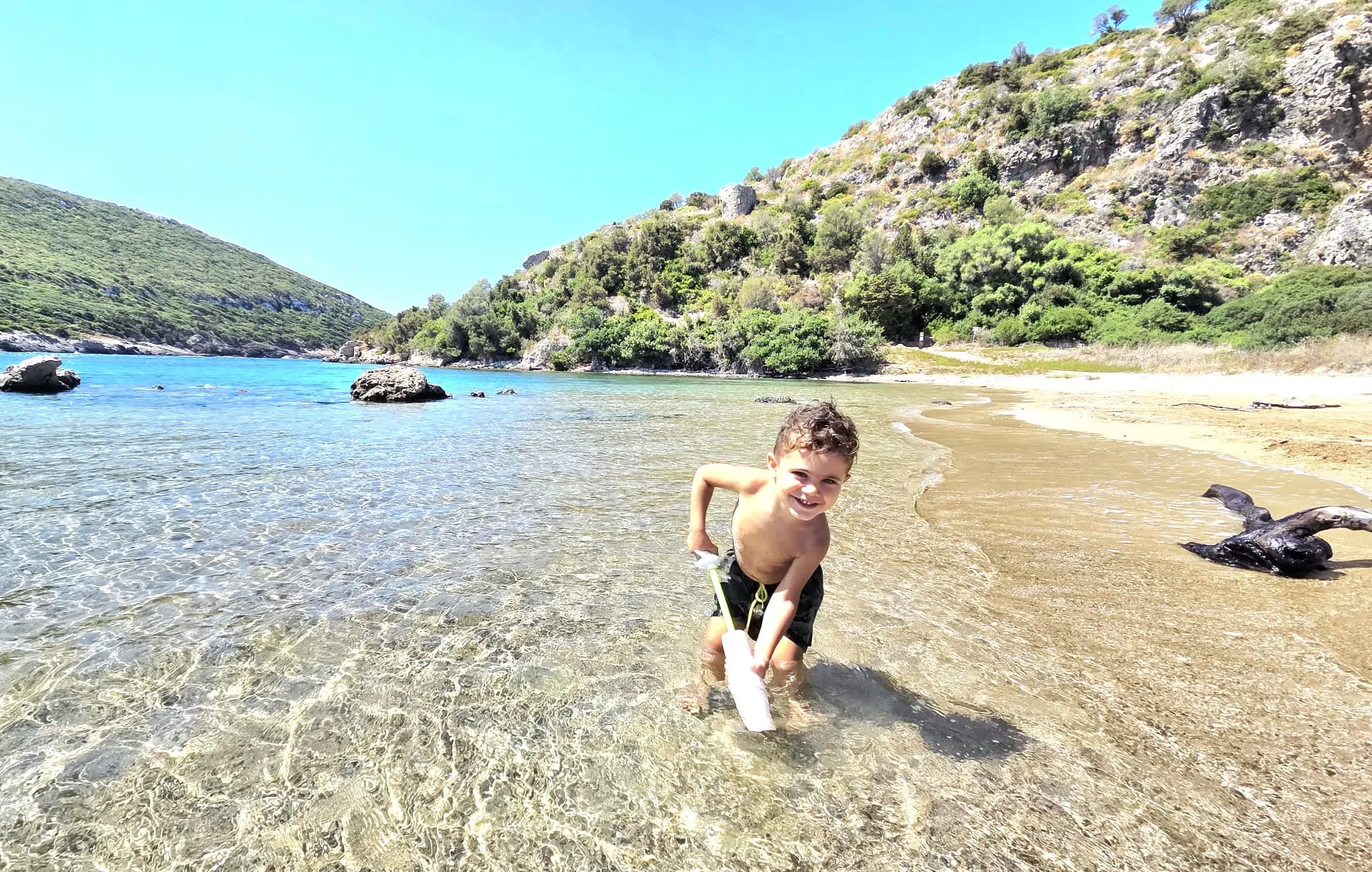 Un bambino gioca nell’acqua bassa e trasparente di una caletta