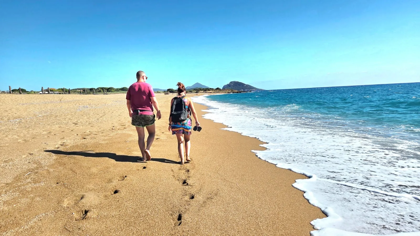 Una coppia passeggia sulla sabbia dorata in riva al mare
