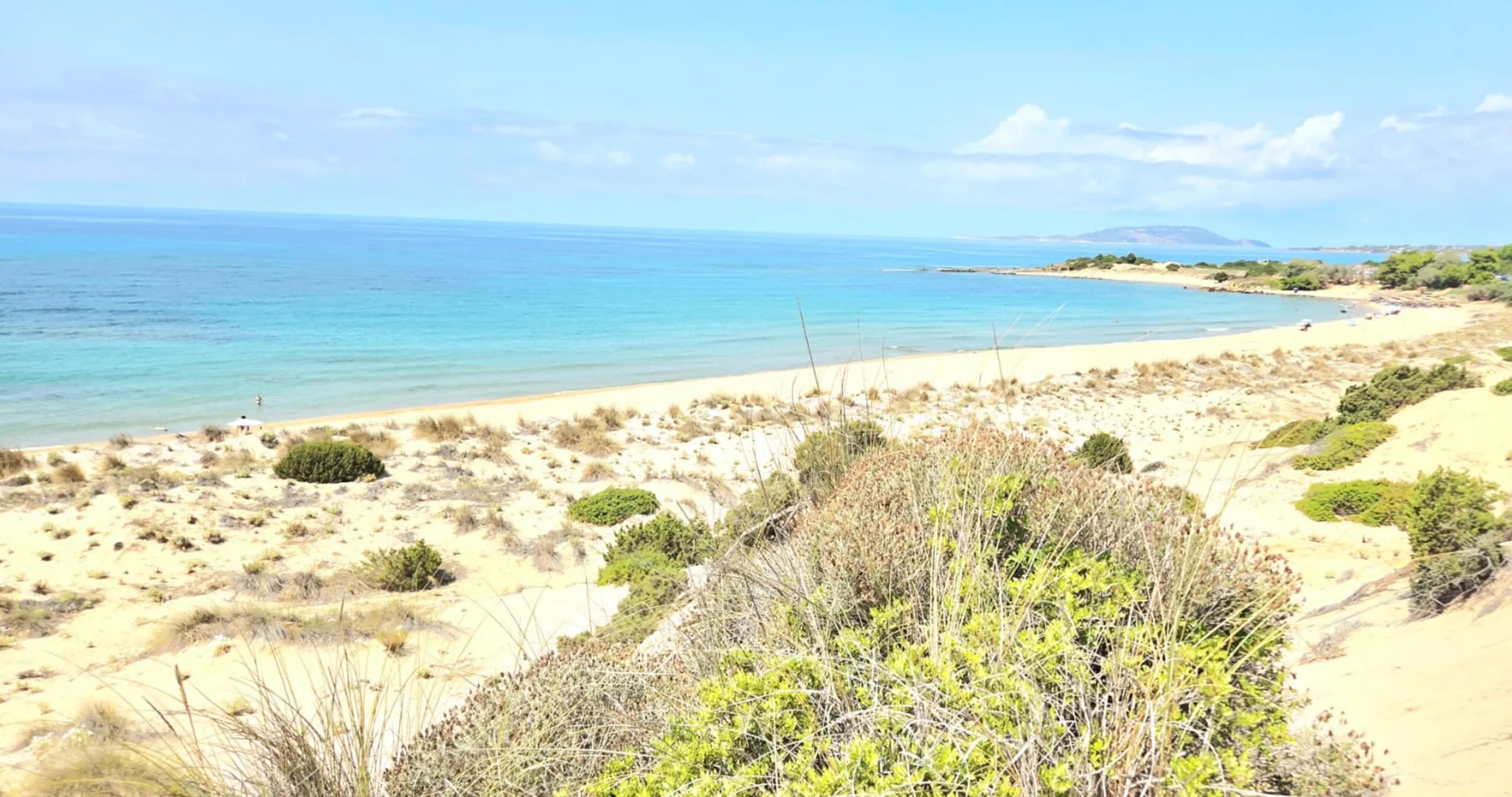 Dune con la macchia mediterranea e una lunga spiaggia sul mare turchese