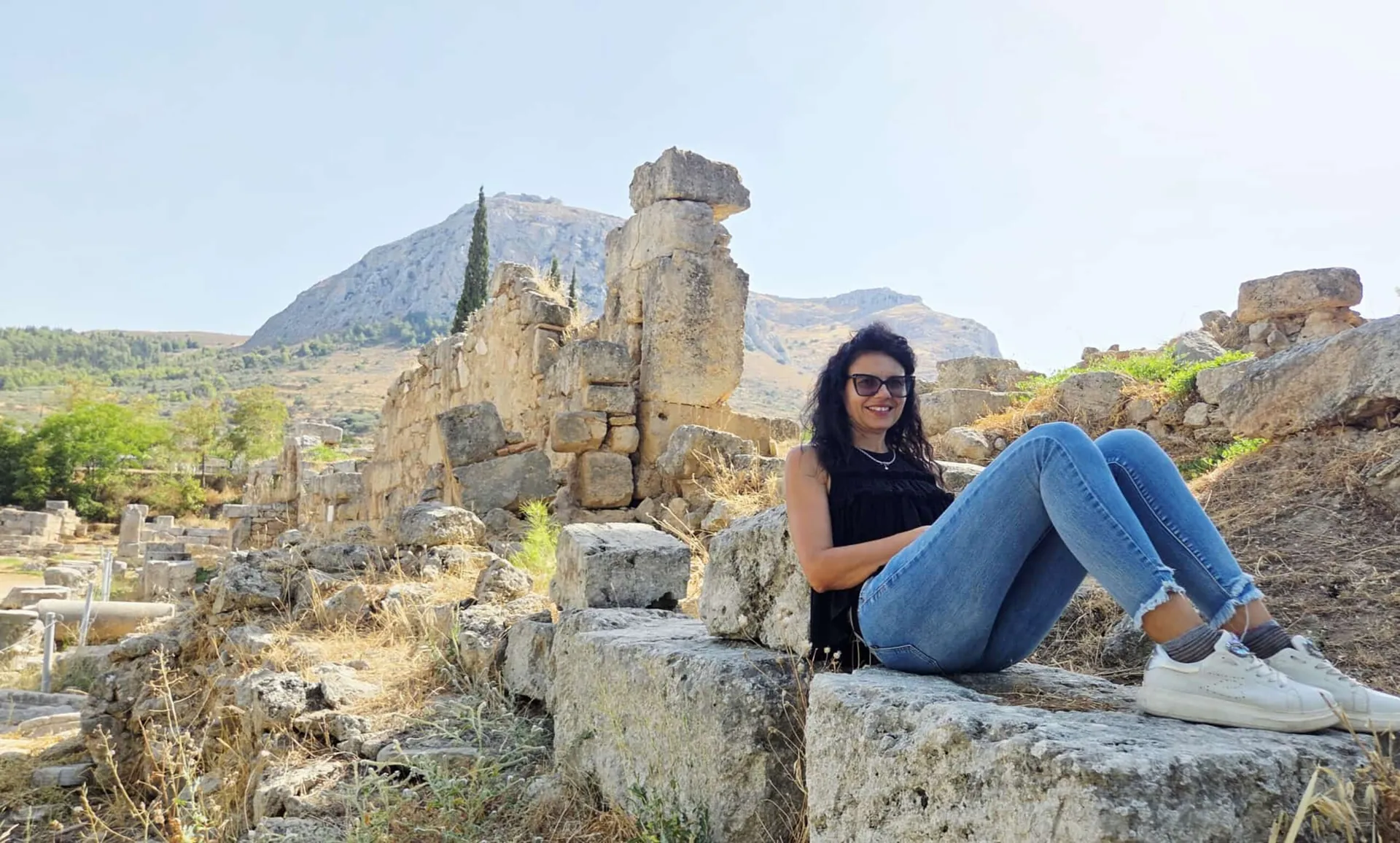 Una ragazza seduta tra le rovine di pietra di un sito archeologico